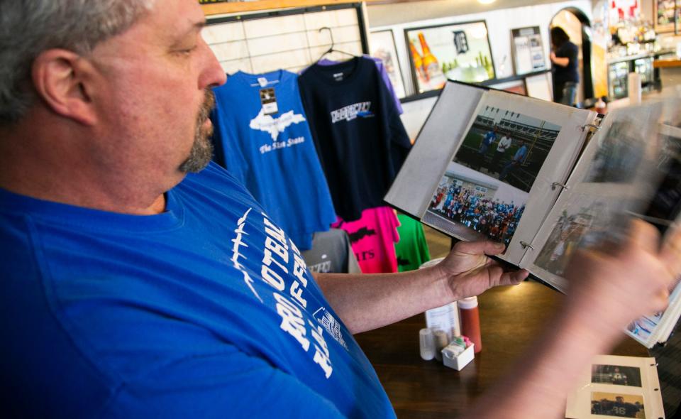 Yooperman's Bar and Grill owner Donnie Stefanski flips through photos of tailgates over the years at Detroit Lions games as he stood inside his bar in Goetzville on Saturday, April 28, 2018 in Michigan's Upper Peninsula.
