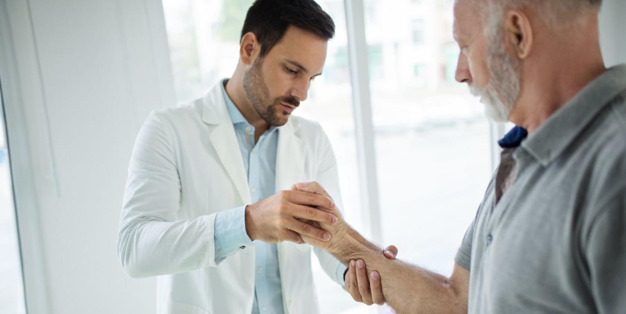 senior man having his wrist examined by a doctor