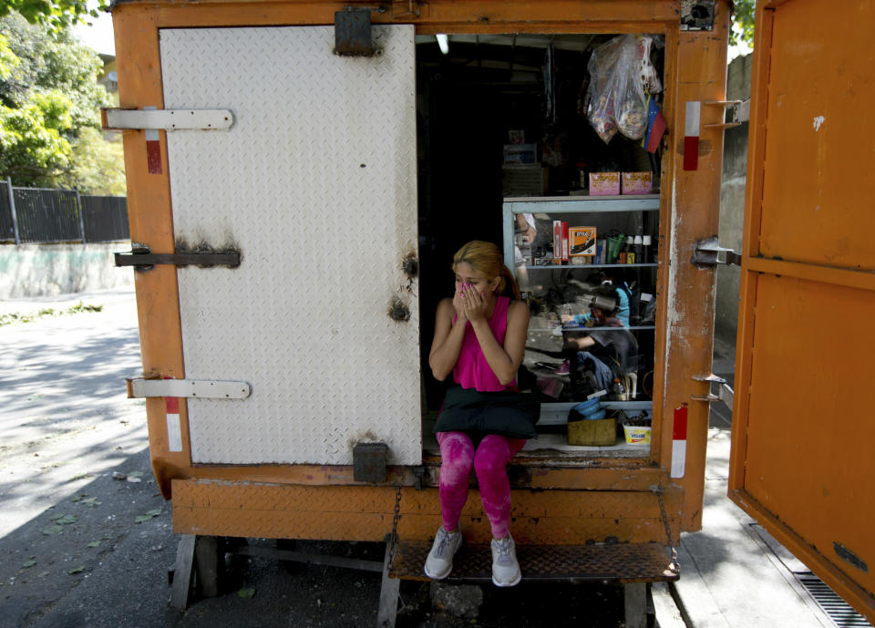 A resident of the San Jose del Avila's neighborhood covers her nose from the lingering odor of tear gas fired by Venezuelan Bolivarian National Police a day prior, in Caracas, Venezuela, Tuesday, Jan. 22, 2019. Working class neighborhoods in Venezuela's capital sifted through charred rubble and smoldering trash on Tuesday, following a day of isolated protests in response to the arrest of National Guardsmen who mounted an uprising against President Nicolas Maduro. (AP Photo/Fernando Llano)