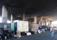 Part of a burned homeless encampment is shown as crews continue to clear debris and shore up a stretch of Interstate 10, Tuesday morning Nov. 14, 2023, in Los Angeles. It will take at least three weeks to repair the Los Angeles freeway damaged in an arson fire, the California Gov. Gavin Newsom said Tuesday, leaving the city already accustomed to soul-crushing traffic without part of a vital artery that serves hundreds of thousands of people daily. (Dean Musgrove/The Orange County Register via AP)