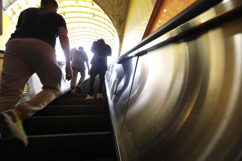 NORTH HOLLYWOOD, CA - JUNE 30, 2022 - - Commuters make their way up an escalator after arriving at the North Hollywood Metro station in North Hollywood on June 30, 2022. The Metro board approved the $120 million five year pilot program to add 300 hundred uniformed workers on rails and buses with the aim of making riders feel safe on the system this fall. The ambassadors will be a catch-all for the system, doing everything from helping with directions to pointing people to homeless services. (Genaro Molina / Los Angeles Times)