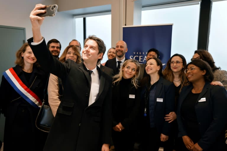 Le Premier ministre Gabriel Attal et le ministre des Services Publics Stanislas Guerini (arrière-plan au centre) posent parmi le personnel de "France Services"dans leur structure à Sceaux, le 23 avril 2024 (Ludovic MARIN)