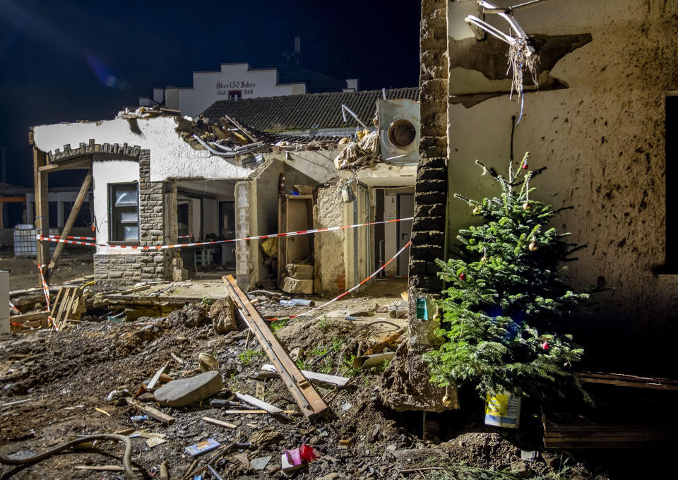 A Christmas tree leans a wall of a damaged house in Mayschoss in the Ahrtal valley, southern Germany, Tuesday, Dec.14, 2021. Amid the mud and debris still clogging the streets from last summer's devastating floods, residents of the Ahr Valley in western Germany are trying to spark some festive cheer with Christmas trees. (Photo/Michael Probst)