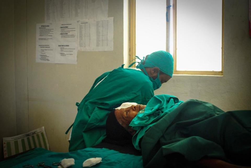 Bugune, still under anaesthetic, lies on the operating table after receiving the simple and cheap eyelid surgery that saved her sight. (Photo: Tom Gardner)
