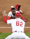 Philadelphia Phillies' Roman Quinn dives into third base safely as third-base coach Dusty Wathan (62) directs during the second inning of a baseball game against the Milwaukee Brewers, Monday, May 3, 2021, in Philadelphia. (AP Photo/Derik Hamilton)