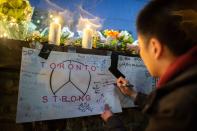 <p>A man writes a message on a sign during a vigil April 24, 2018 in Toronto, Canada, near the site of the previous day’s deadly street van attack. (Photo: Geoff Robins/AFP/Getty Images) </p>