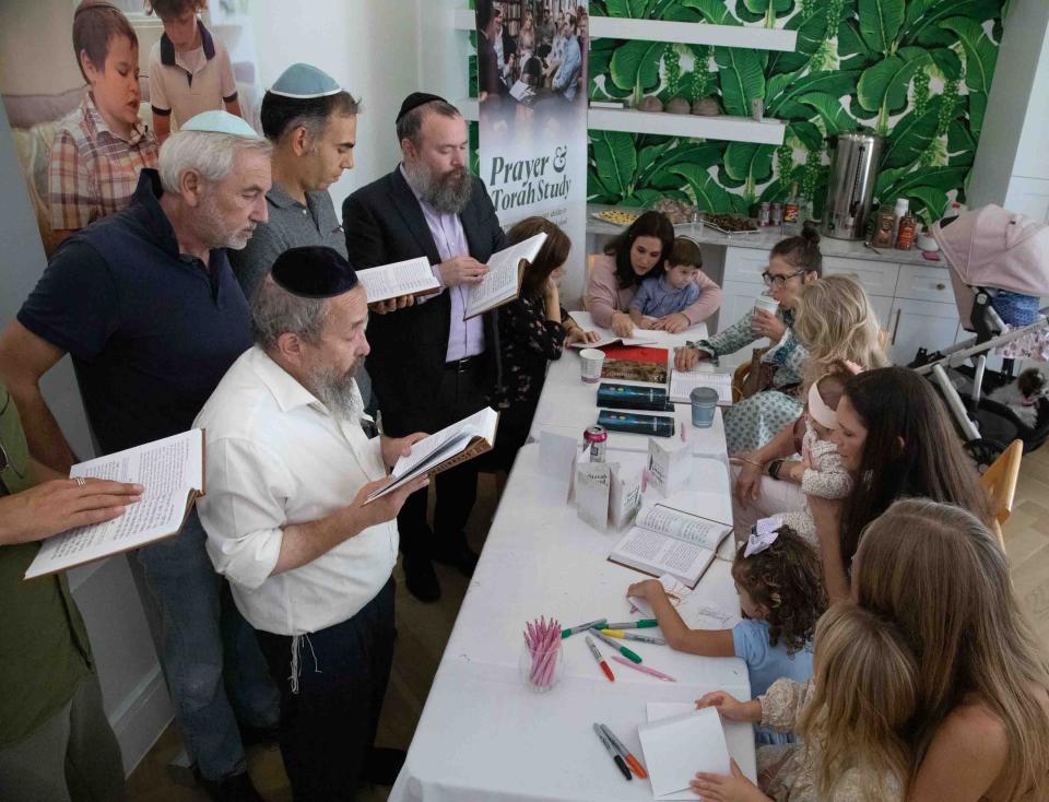 Men sing a song from a tehillim (Psalms) songbook at the "Mitzvah for Israel" pop-up store at The Chabad House while other members of the public write cards of support for Israel following the Oct. 7 Hamas attacks.