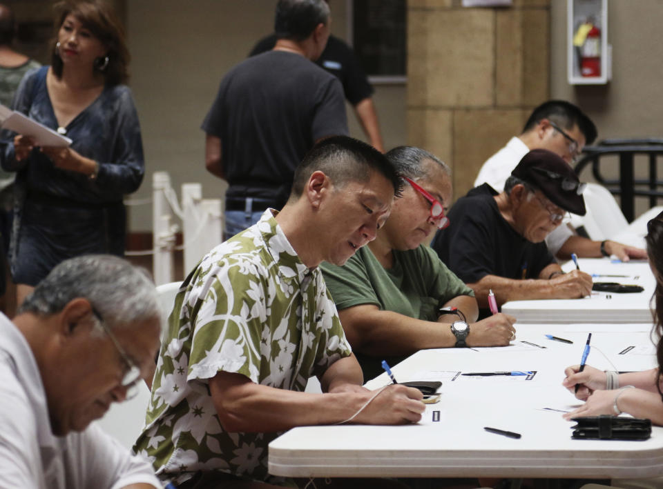 Congressional candidate Lt. Gov. Doug Chin, center, signs in to vote at an early polling location in Honolulu on Thursday, Aug. 9, 2018. Hawaii's weekend primary election will most likely settle the outcome of this year's major races. (AP Photo/Jennifer Sinco Kelleher)