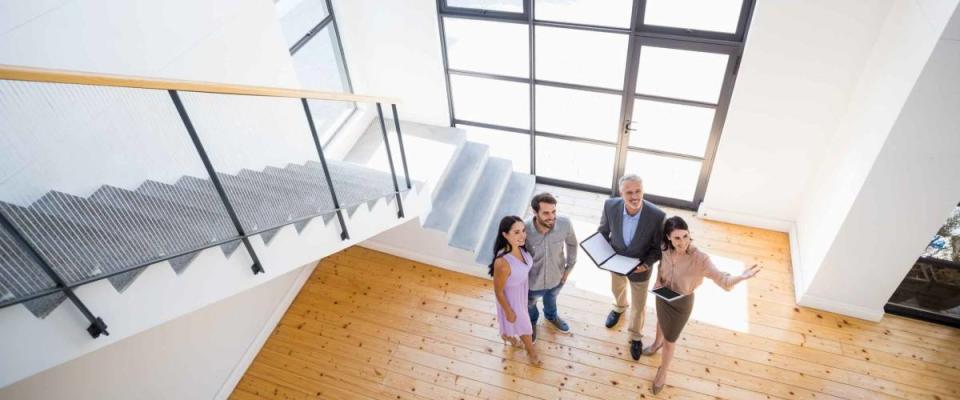 Real estate agent showing new house to couple with digital tablet