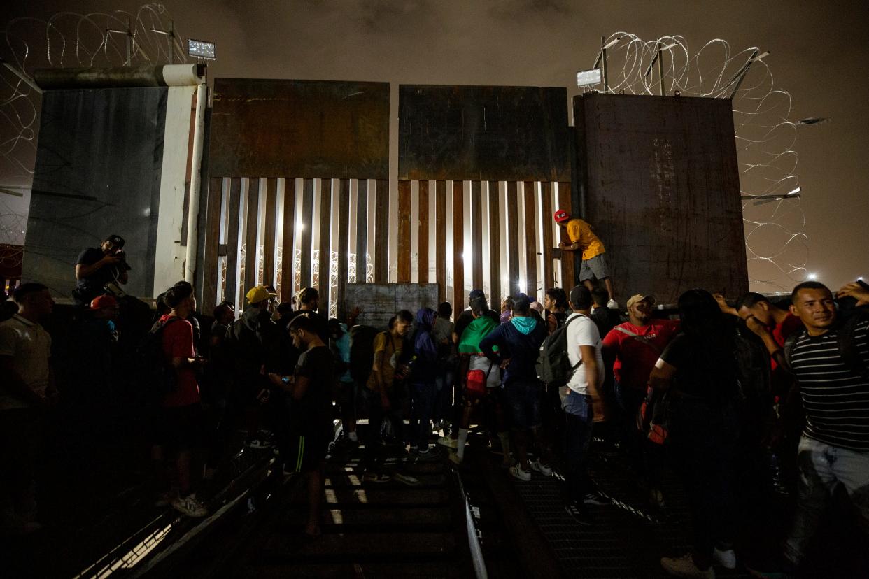 Migrants plead with U.S. Customs and Border Protection officers on Aug. 7 to allow them entry into the U.S. as they stand next to a gate on the northbound railroad bridge in Juárez, Mexico, that leads into El Paso, Texas, after a rumor on social media claimed that they would be allowed enter to seek asylum.