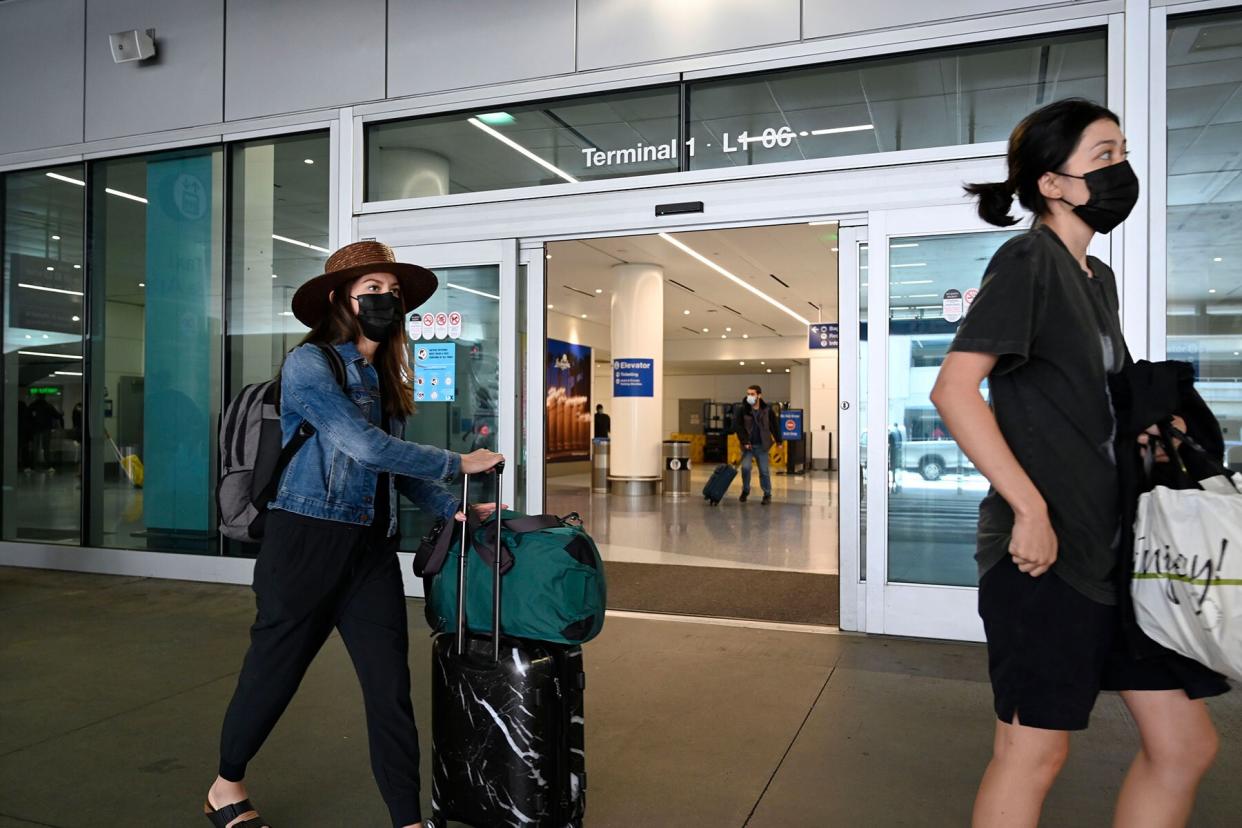 Travelers at Los Angeles International Airport wearing their face coverings
