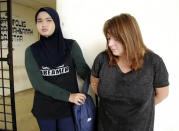 In this Thursday, Oct. 18, 2018, image from video, handcuffed British woman Samantha Jones, right, is escorted to a van at Alor Setar High Court in Kedah, Malaysia. Malaysian police said Friday, Oct. 19, 2018, that the British woman was detained on the resort island of Langkawi for allegedly stabbing her husband to death. Langkawi police chief Supt. Mohamad Iqbal Ibrahim said investigators found a 12 inch-long kitchen knife stained with blood in the couple's home where John William Jones, 62, was found dead Thursday. (StarTV via AP)