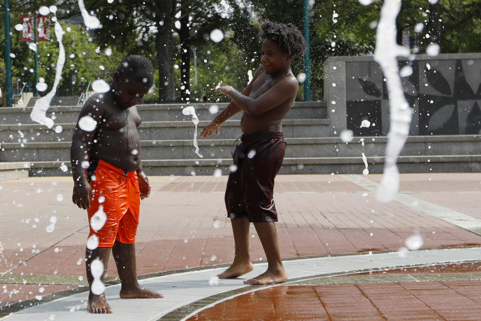 Kai Frazier and Chance Seawright, brothers visiting from Aiken, South Carolina, cool off while playing in the Fountain of Rings in Centennial Olympic Park, Monday, Aug. 12, 2019, in Atlanta. (AP Photo/Andrea Smith)