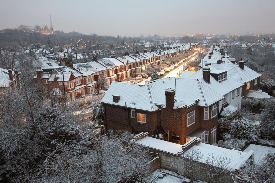 first-time buyers High level aerial view of Muswell Hill in winter with snow on suburban houses, Alexandra Palace in distance and street lights in early morning.