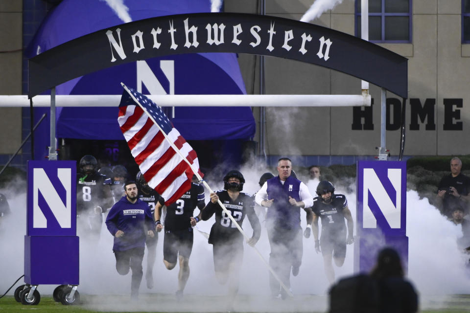 FILE - Northwestern coach Pat Fitzgerald, right, leads the team onto the field for the team's NCAA college football game against Miami (Ohio) on Sept. 24, 2022, in Evanston, Ill. Approximately 1,000 former Northwestern University athletes sent a letter, obtained by The Associated Press on Thursday, Aug. 17, 2023, condemning hazing while defending the school's culture, saying allegations of abuse within the football program and other men's and women's teams do not reflect their experiences. Coach Fitzgerald was fired in July 2023 after 17 seasons amid the hazing scandal. (AP Photo/Matt Marton, File)