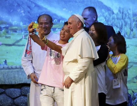 Pope Francis (C) poses for a "selfie" with young people during a meeting with Asian youths at the Solmoe Shrine in Dangjin August 15, 2014. REUTERS/Ahn Young-joon/Pool