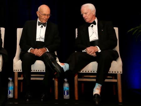 Apollo 11 astronaut Michael Collins (L) looks at socks picturing Saturn V rocket worn by Apollo 9 astronaut Rusty Schweikart as they take part in a panel discussion on the 50th anniversary of Apollo 11 launch, in Cocoa Beach