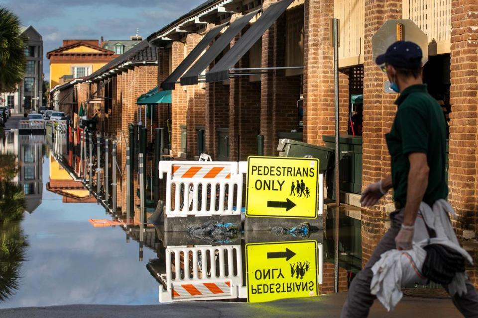 A pedestrian walks by a flooded Market St. as a king tide rolls into the popular tourist shopping area in Charleston, S.C. Sunday, Nov. 15, 2020. Charleston has remained relatively unscathed this hurricane season. That means more time to mull a $1.75 billion proposal by the Army Corps of Engineers that features a sea wall along the city’s peninsula to protect it from deadly storm surge during hurricanes. (AP Photo/Mic Smith)