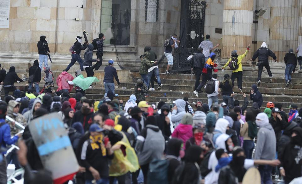 Anti-government protesters clash with the police during a nationwide strike, at Bolivar square in downtown Bogota, Colombia, Thursday, Nov. 21, 2019. Colombia's main union groups and student activists called for a strike to protest the economic policies of Colombian President Ivan Duque government and a long list of grievances. (AP Photo/Fernando Vergara)