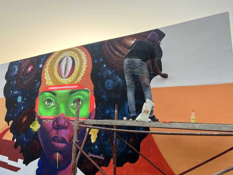 An artist paints a futuristic mural in real time on Dec. 28, 2022 at the 2022 Afrochella Festival at El Wak Stadium in the greater Accra region of Ghana. (theGrio Photo/Chinekwu Osakwe)