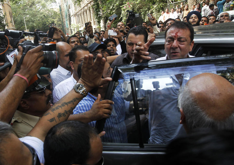 Bollywood star Sanjay Dutt, right, gestures to the media as he arrives to surrender before a court in Mumbai, India, Thursday, May 16, 2013. Dutt has been sentenced to five years in prison for a 1993 weapons conviction linked to a deadly terror attack in Mumbai that killed 257 people. The 53-year-old actor served 18 months in jail before being released on bail in 2007 pending an appeal. The Supreme Court reduced his prison sentence to five years from the six-year term initially handed down. (AP Photo/Rajanish Kakade)
