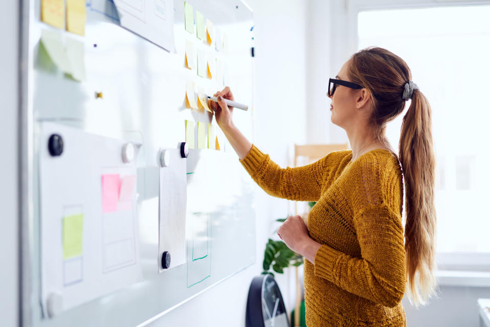 a woman writing on a whiteboard