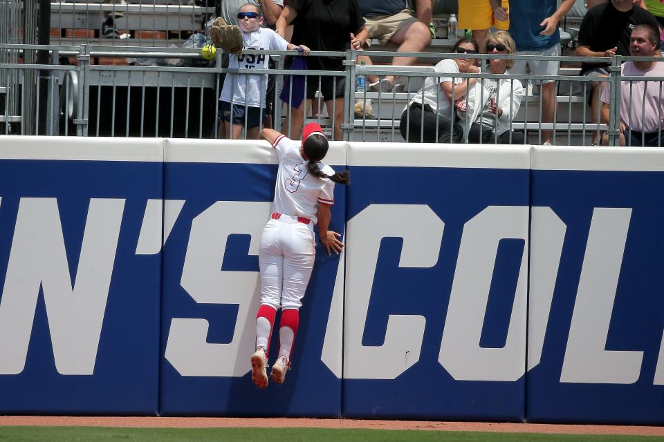 The ball goes over the wall past Utah's Haley Denning (3) for a home run in the second inning of a softball game between Utah and Washington in the Women's College World Series at USA Softball Hall of Fame Stadium in Oklahoma City, Friday, June 2, 2023. Washington won 4-1.