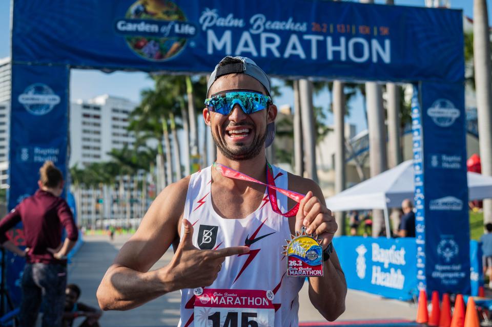 Men's overall marathon race winner Andres Sernas, Cali, Colombia, poses for a picture holding his race completion medal on South Flagler Drive during the Garden of Life Palm Beaches Marathon on Sunday, December 11, 2022, in downtown West Palm Beach, FL. Thousands of runners participated in races held over the weekend, which ranged from a 5K all the way to a 26.2 mile-long marathon.