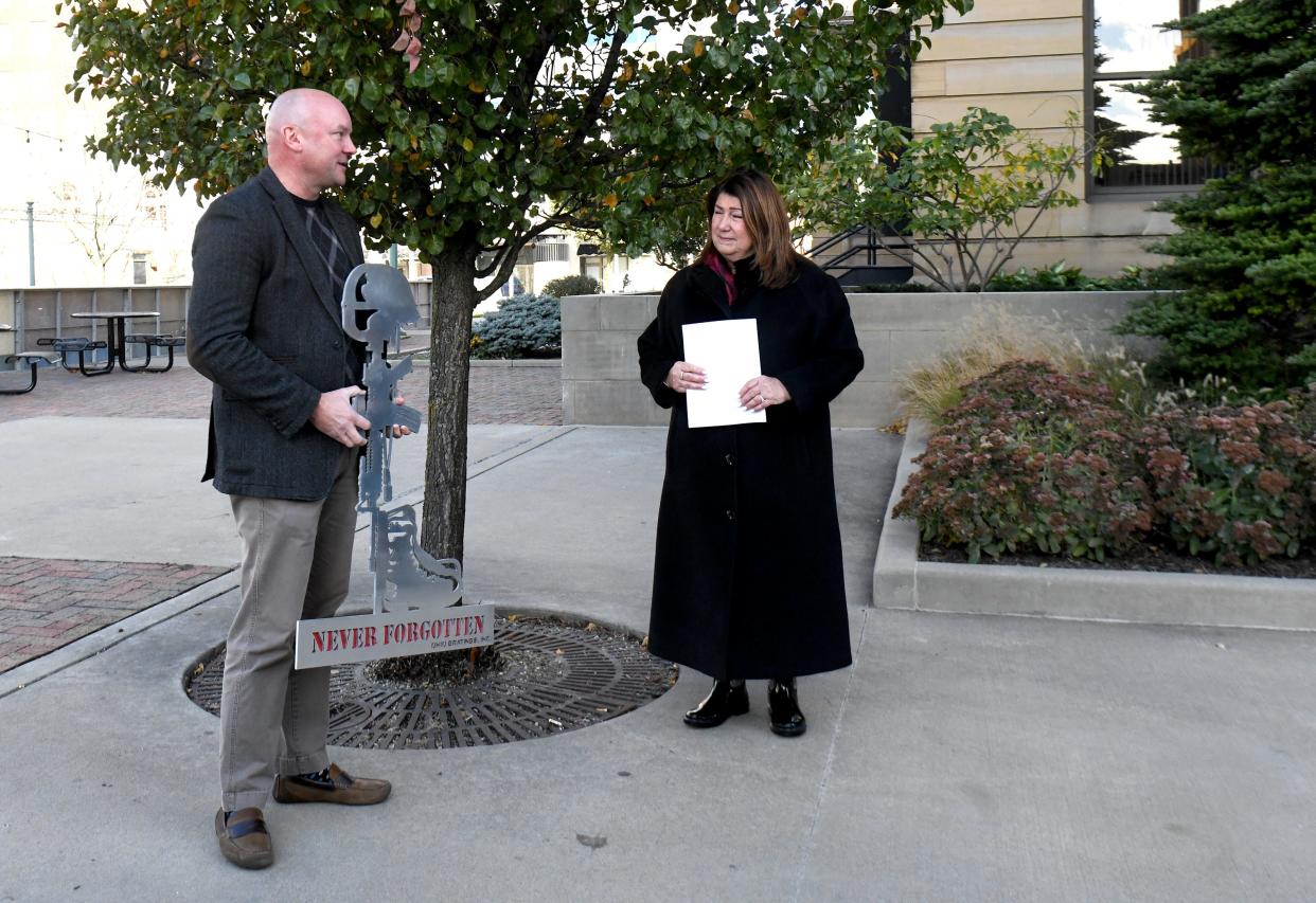 Shaun Eller, chief business officer of Ohio Gratings Inc., presents a battlefield cross to Stark County Common Pleas Judge Taryn L. Heath to be placed at the witness tree outside the Stark County Courthouse.
