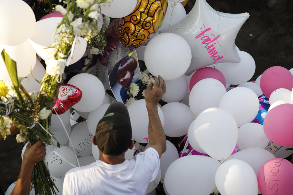 Family members place balloons and flower arrangements on the grave of 7-year-old murder victim Fatima in Mexico City, Tuesday, Feb. 18, 2020. Fatima's body was found wrapped in a bag and abandoned in a rural area on Saturday. Five people have been questioned in the case, and video footage of her abduction exists. (AP Photo/Marco Ugarte)