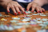 Francisca Perez, 84, rearranges puzzle pieces, a part of her regular exercise to recover from rheumatoid arthritis, Wednesday, June 30, 2021, in Chicago's Little Village neighborhood. She suffers from a heart condition and depression, among other ailments. Her daughter, Eugenia Rodriguez, hasn't been eligible for insurance coverage after overstaying a visitor visa from Mexico. She used to wake up every two or three hours at night to check on her mother. Since getting health insurance through the Illinois program, her mother has all the medications she needs. (AP Photo/Shafkat Anowar)