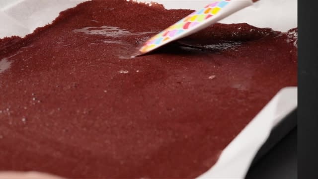 Spreading batter on a swiss roll tin with a spatula