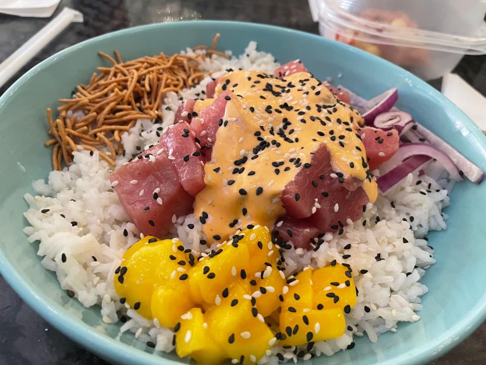 Paradise Que's Volcano Poke offers a choice of raw tuna or salmon topped in Paradise Volcano sauce and served — along with sliced red onion, chopped mango and crunchy noodles — on white rice, mixed greens or zoodles.