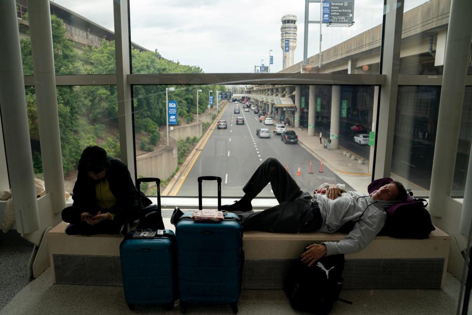 Carl Salazar (right) sleeps at Ronald Regan Washington National Airport while waiting for a delayed United flight on July 19, 2024 in Washington, DC.