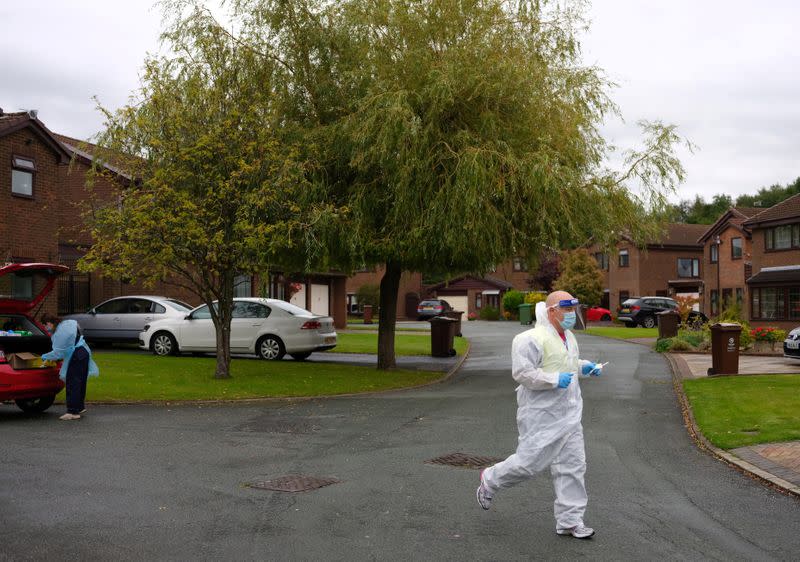 A member of the community swabbing team jogs across a housing estate as he carries out a doorstep COVID-19 testing following the outbreak of the coronavirus disease (COVID-19) in Chadderton, Britain