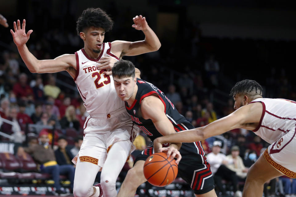 Southern California forward Isaiah Mobley, right, makes contact with Utah guard Lazar Stefanovic (20) as forward Max Agbonkpolo (23) defends during the first half of an NCAA college basketball game in Los Angeles, Wednesday, Dec. 1, 2021. (AP Photo/Alex Gallardo)