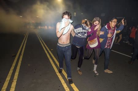 Protesters retreat while police officers deploy teargas to disperse a crowd comprised largely of student protesters during a protest against police violence in the U.S., in Berkeley, California early December 7, 2014. REUTERS/Noah Berger