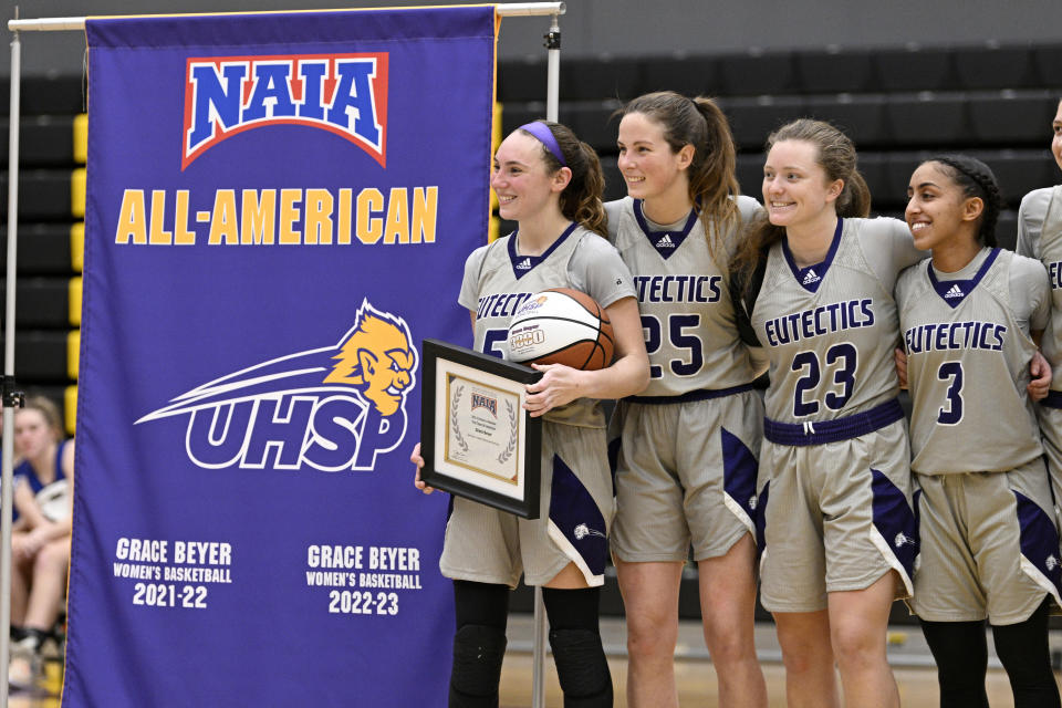 University Health Sciences and Pharmacy guard Grace Beyer holds a ball and plaque as her All-American achievement is honored following an NAIA college basketball game against Cottey College Thursday, Feb. 22, 2024, in St. Louis. The eyes of the sports world have been trained on Iowa star Caitlin Clark's pursuit of women's basketball scoring history, but some have noticed that Grace Beyer at a tiny NAIA school is the only active player with more points than Clark. (AP Photo/Jeff Le)