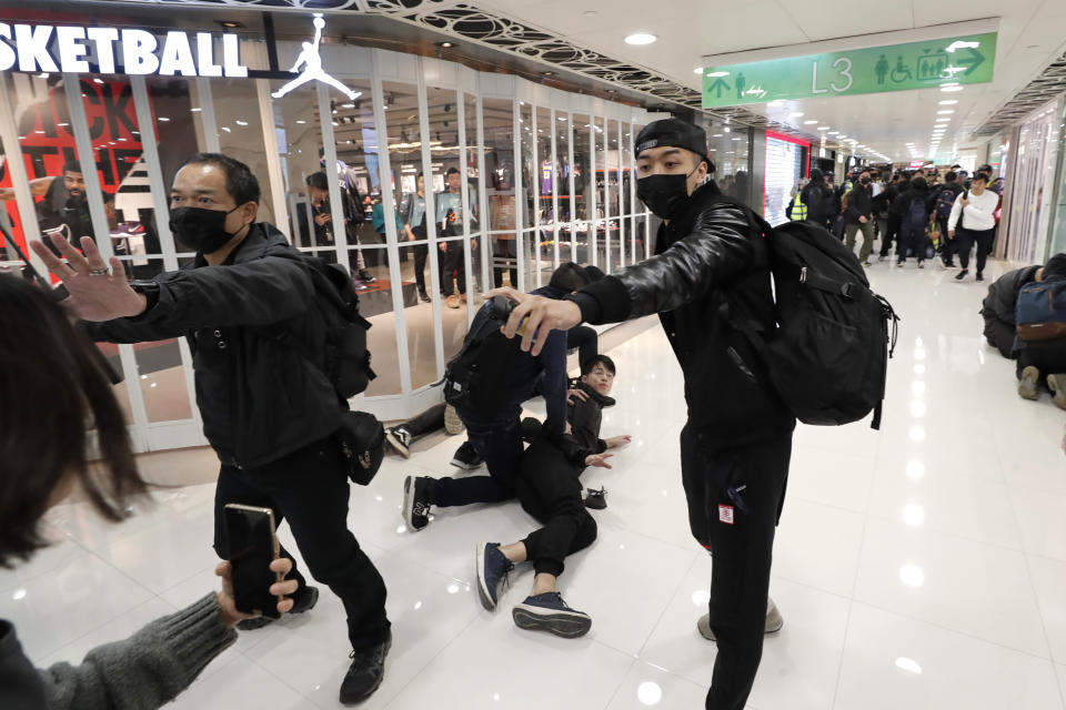 An undercover policeman points a can of pepper spray as others detain a protester during a demonstration at a shopping mall popular with traders from mainland China near the Chinese border in Hong Kong, Saturday, Dec. 28, 2019. Protesters shouting "Liberate Hong Kong!" marched through a shopping mall Saturday to demand that mainland Chinese traders leave the territory in a fresh weekend of anti-government tension. (AP Photo/Lee Jin-man)