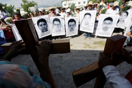 Relatives of missing students of the Ayotzinapa Teacher Training College, Raul Isidro Burgos, stand together as they hold photographs of the missing students and crosses with the names of three students who were killed during clashes with police in late September, in Iguala October 27, 2014. REUTERS/Henry Romero