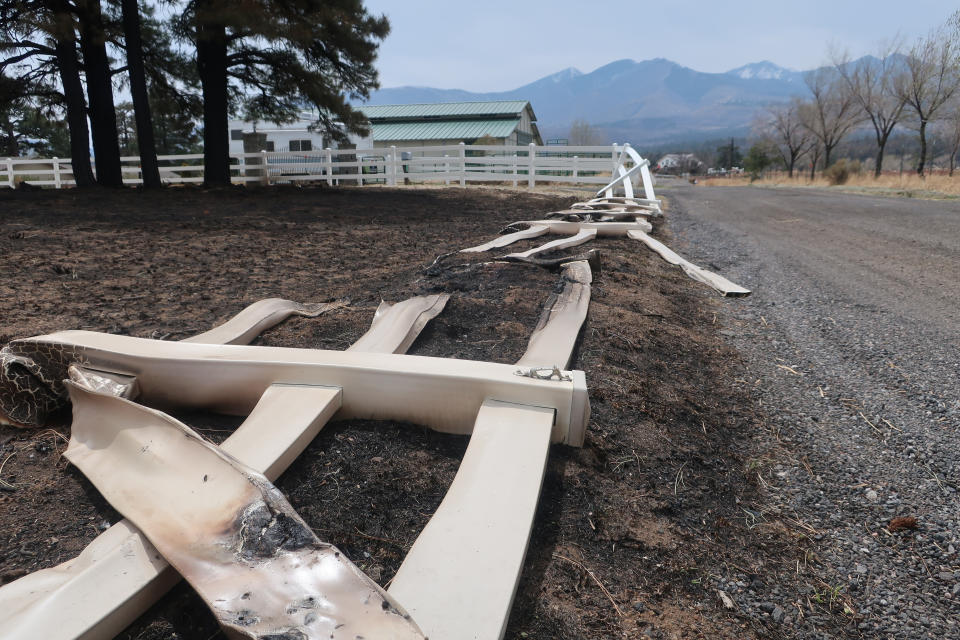 Fencing around a property known as Girls Ranch lies melted to the ground, Tuesday, April 26, 2022, after a massive wildfire swept through the outskirts of Flagstaff, Ariz. The blaze that started Easter Sunday burned about 30 square miles and more than a dozen homes, hopscotching across the parched landscape. (AP Photo/Felicia Fonseca)