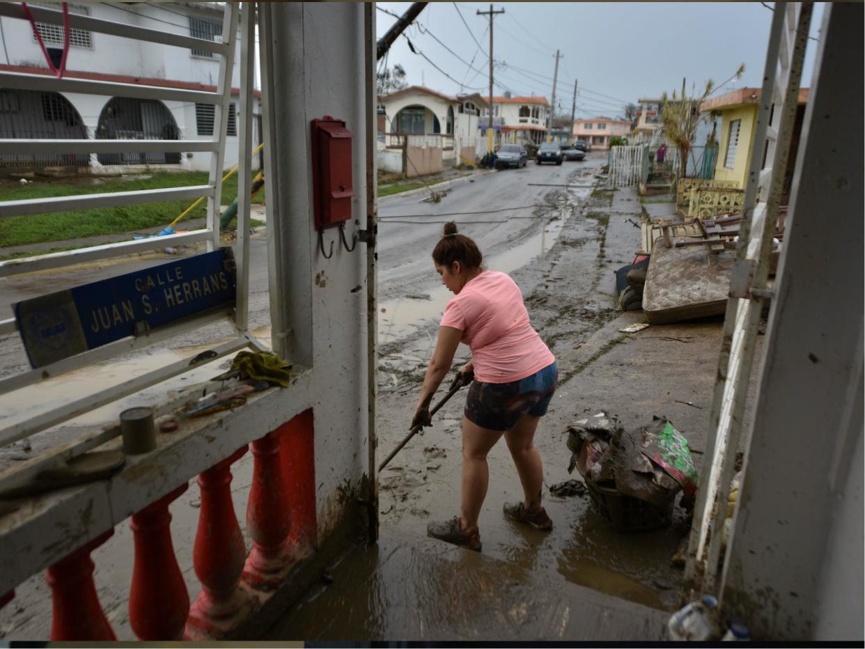 A woman removes mud from her damaged house in Toa Baja, 35 km from San Juan, Puerto Rico, on 23 September 2017: Getty