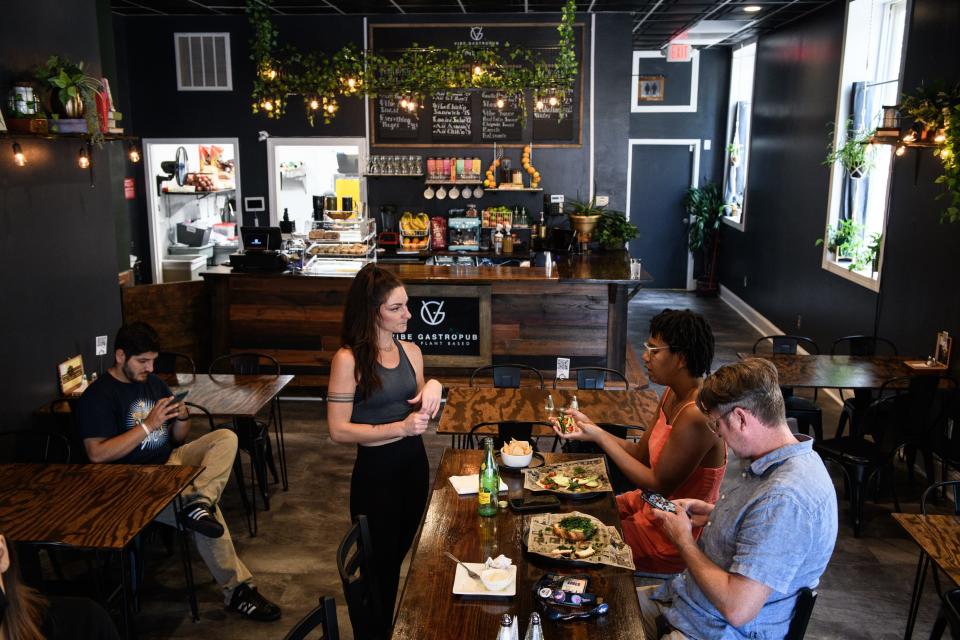 Ambery Edge, center, talks with customers Michele and Gerard Falls at Vibe Gastropub in downtown Fayetteville.