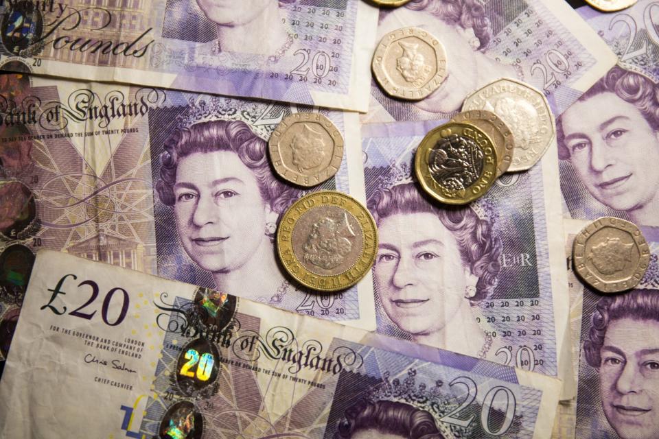 In this photo illustration banknotes of the pound sterling, The Bank of England £20 notes with the image of Queen Elizabeth II and various coins of the pound sterling are seen displayed.