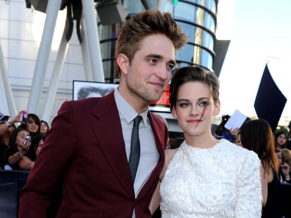 Robert Pattinson, in a maroon suit, and Kristen Stewart, in a white one-sleeved dress, pose for photos during the 2010 premiere of "The Twilight Saga: Eclipse."