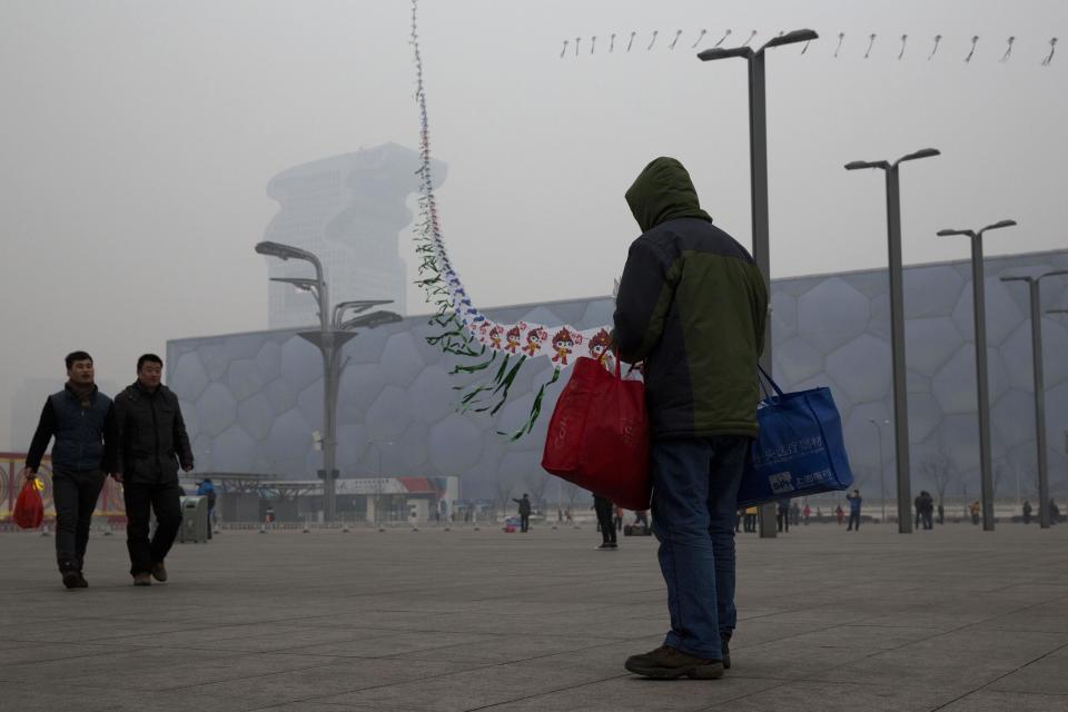 In this picture taken Sunday, Feb. 23, 2014, a street vendor flies kites printed with the Beijing Olympic games mascot image near the Water Cube aquatic center in Beijing, China. The Water Cube _ where U.S. swimmer Michael Phelps made history by winning eight gold medals _ has been transformed into a water park popular among local families. Its operators even peddle purified glacier water under the Water Cube brand for additional income. Beijing, which spent more than $2 billion to build 31 venues for the 2008 Summer Games, is reaping some income and tourism benefits from two flagship venues, though many sites need government subsidies to meet hefty operation and maintenance costs. (AP Photo/Ng Han Guan)