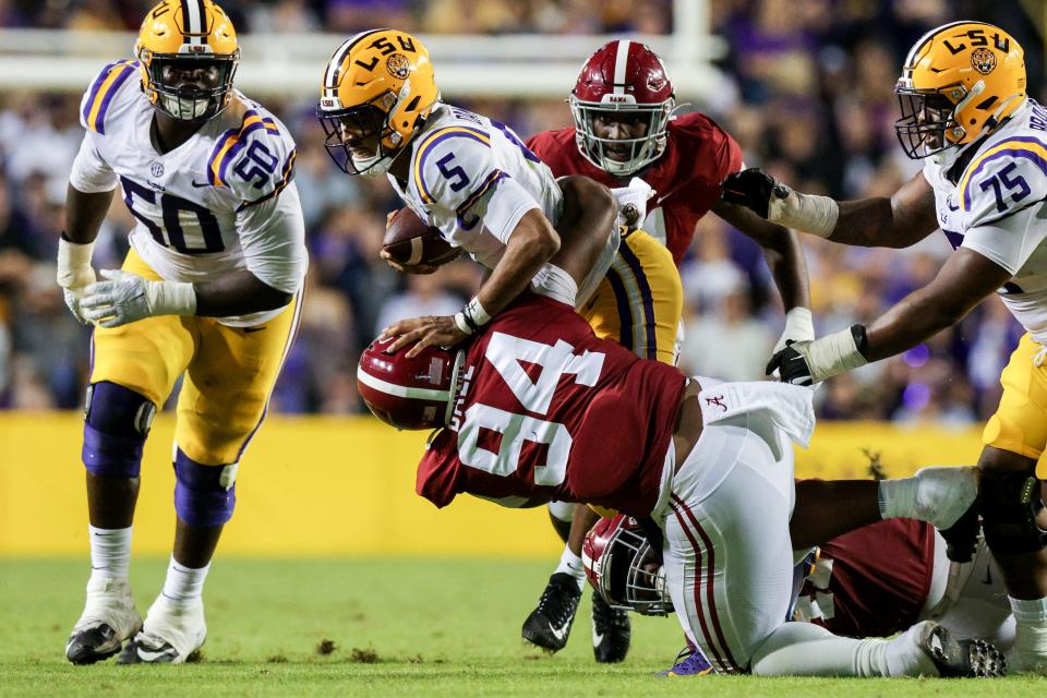 LSU quarterback Jayden Daniels (5) is tackled by Alabama defensive lineman DJ Dale (94) and linebacker Chris Braswell (41) during the second half at Tiger Stadium.