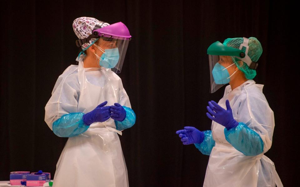 Healthcare workers talk as they wait for residents at a temporary testing center