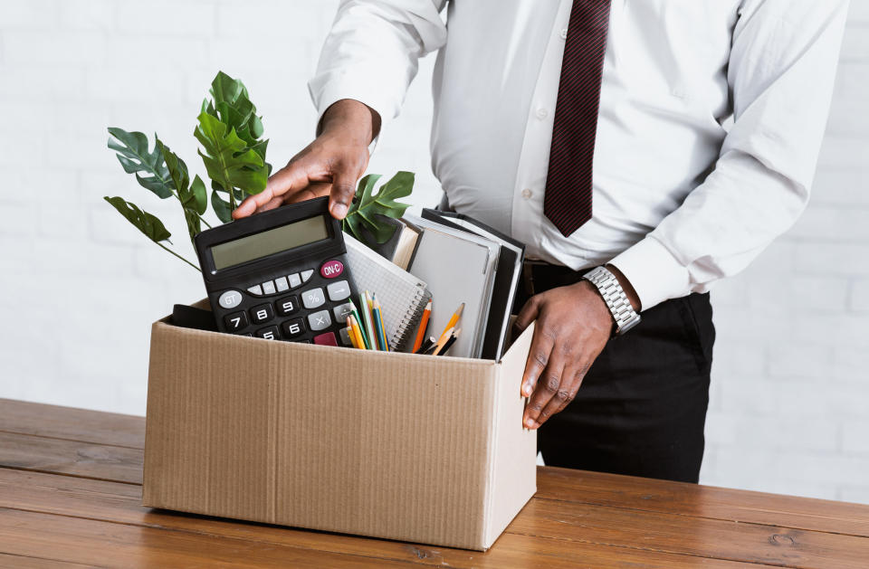 An employee packs their office supplies in a box after quitting