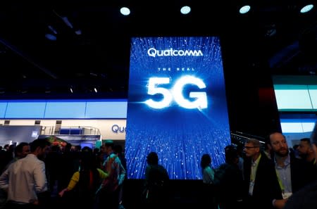 FILE PHOTO: People walk by a video display promoting 5G connectivity at the Qualcomm booth during the 2019 CES in Las Vegas